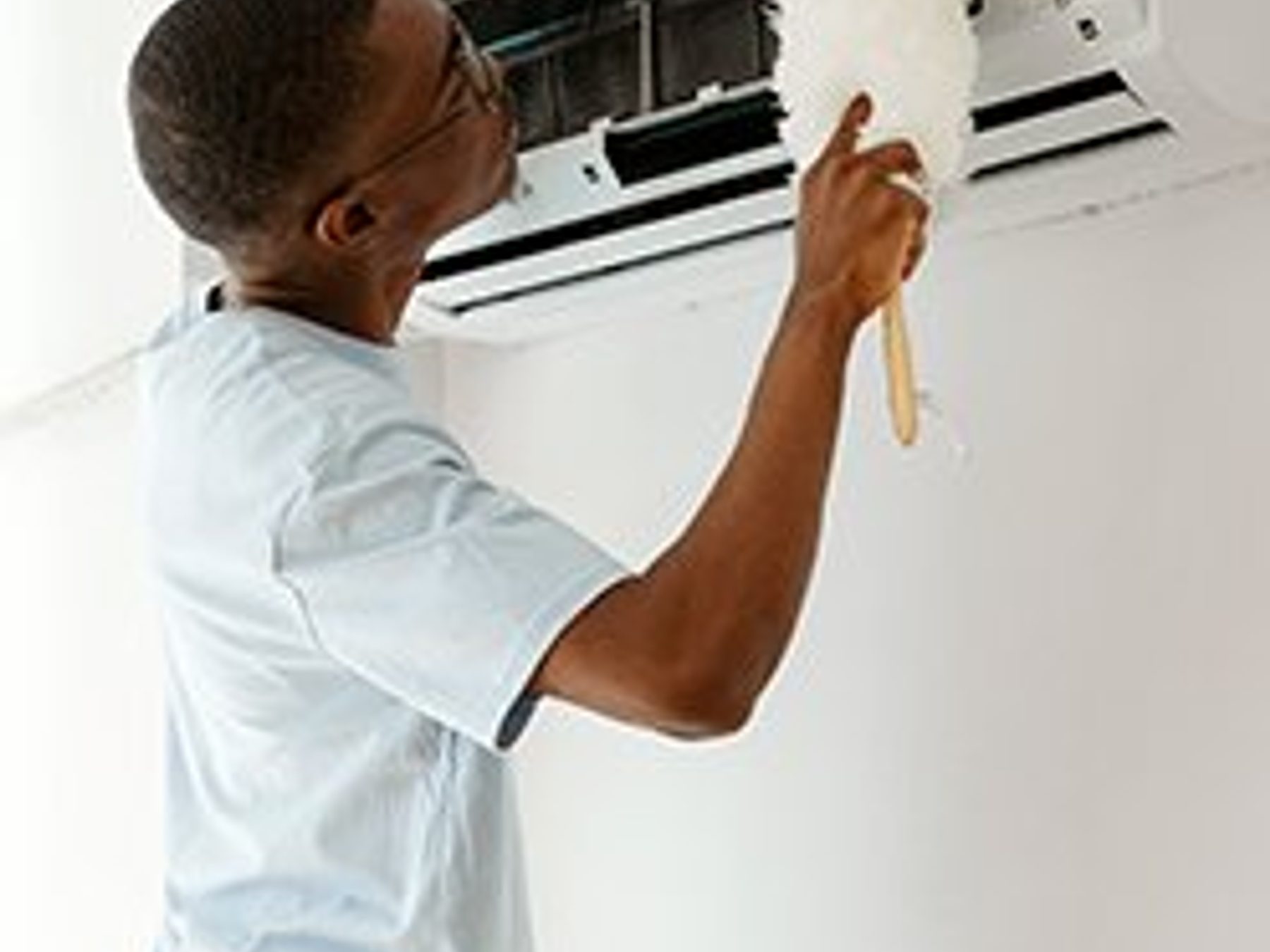A technician testing a wall-mounted thermostat.