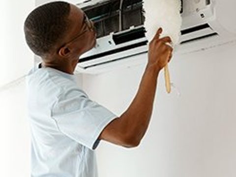 A technician testing a wall-mounted thermostat.