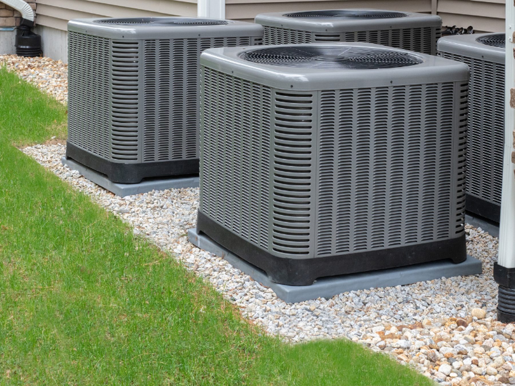 A condenser unit installed on a concrete pad beside a house.
