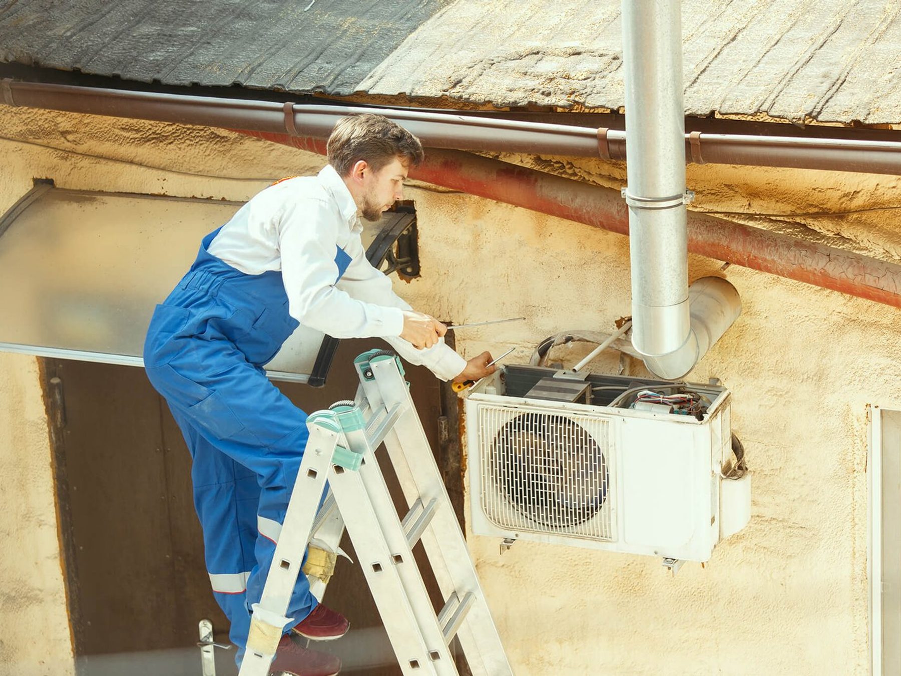 A technician working on an air conditioning condenser unit.